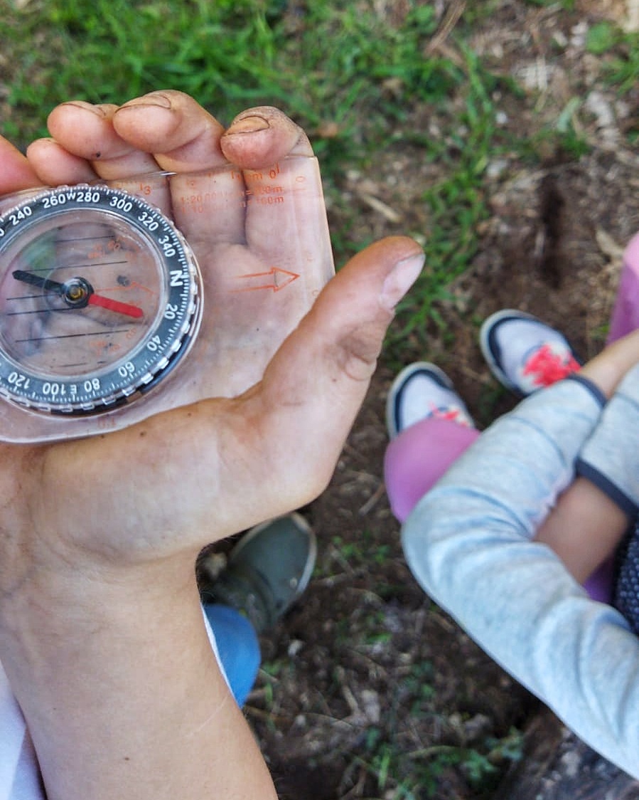 Una piccola mano sporca di terra regge una bussola