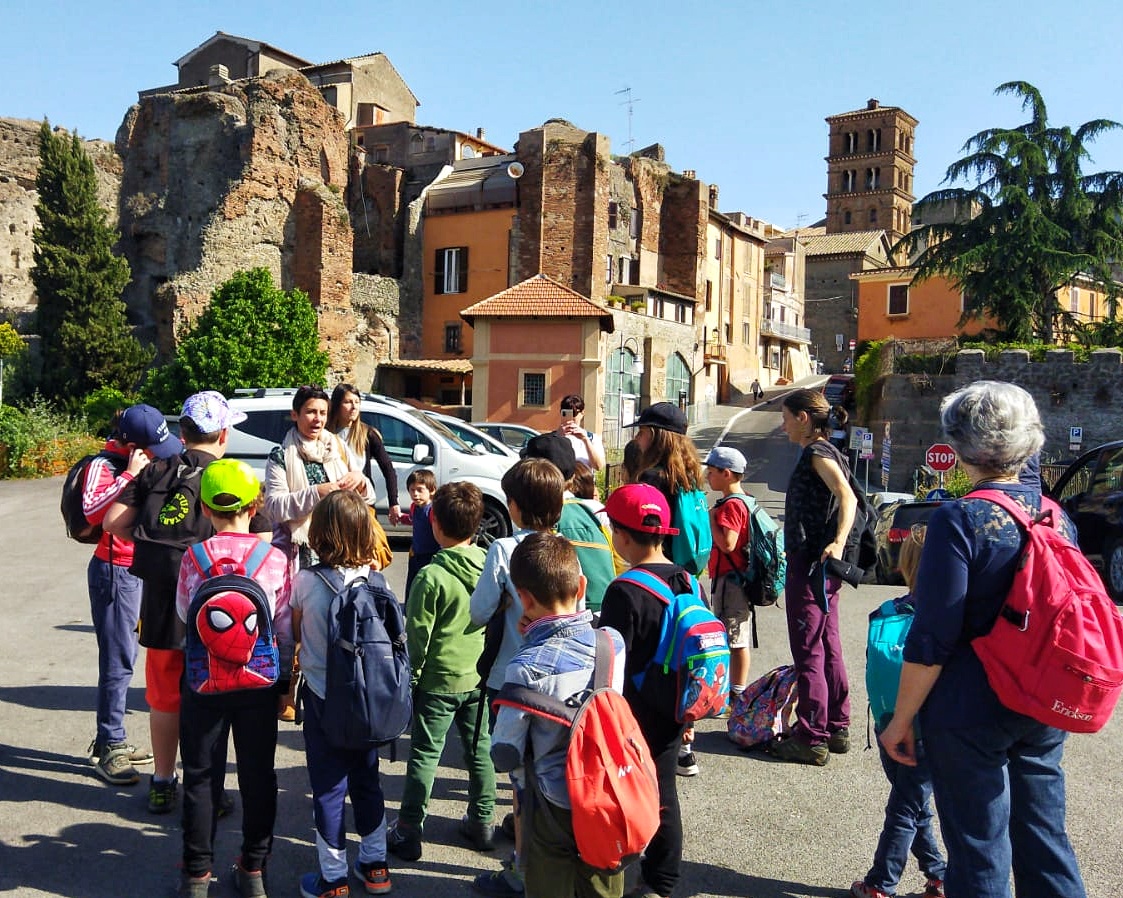 Bambini, bambine e maestre ascoltano la guida durante la gita ad Albano Laziale