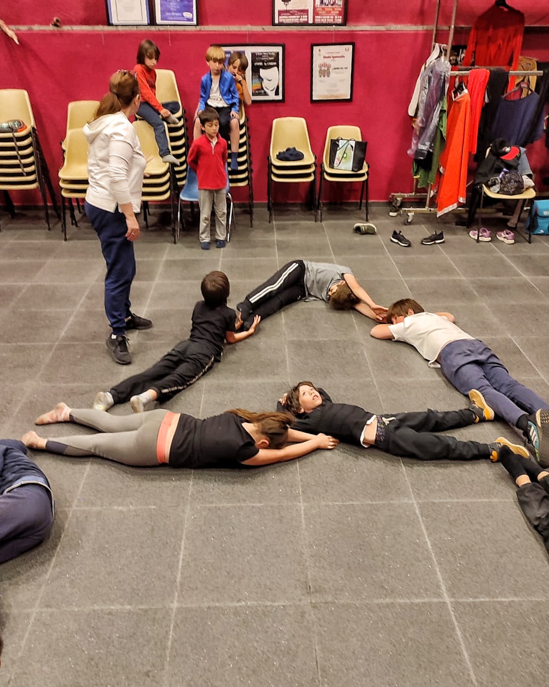 Bambini a lezione di teatro creano le lettere con i loro corpi.